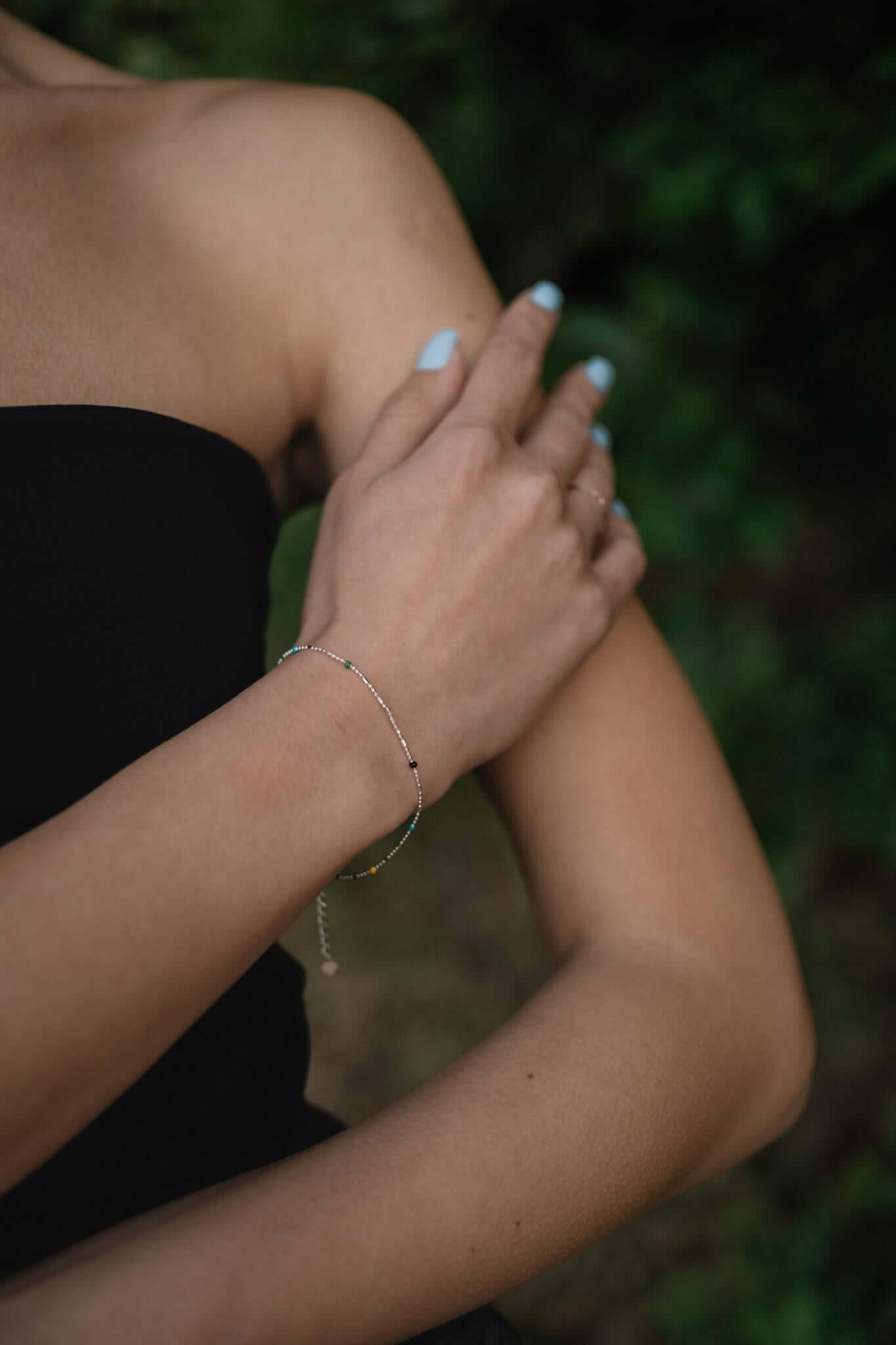 Сребърна многоцветна гривна S925, носена от жена на открито, акцентираща на елегантност и стил.