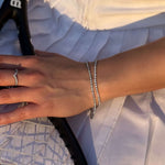 Гривна на ръката с тенис ракета на фона, изработена от неръждаема стомана и с елегантен дизайн.