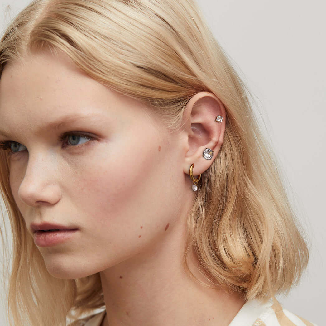 Жена с обеци Блясък с 18К златно покритие, три вида кристали, нежна визия и модерен стил.