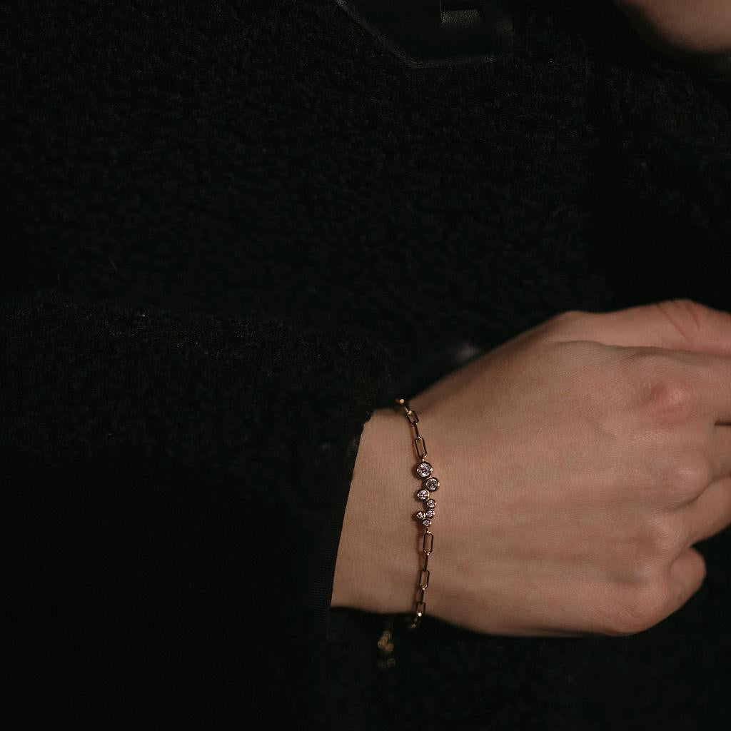 Елегантна сребърна гривна с 18К златно покритие и камъни циркон, носена на ръка.