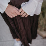 стилна жена с златист пръстен Wave и кремава риза, носеща къса пола на улицата