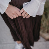 стилна жена с златист пръстен Wave и кремава риза, носеща къса пола на улицата