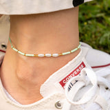 Ръчно изработена бохо гривна за глезен с перлички и мъниста, носена на гол крак с бели обувки.