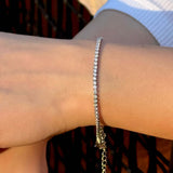 Гривна с инкрустирани камъни, носена на ръката, показваща елегантен дизайн и блясък.