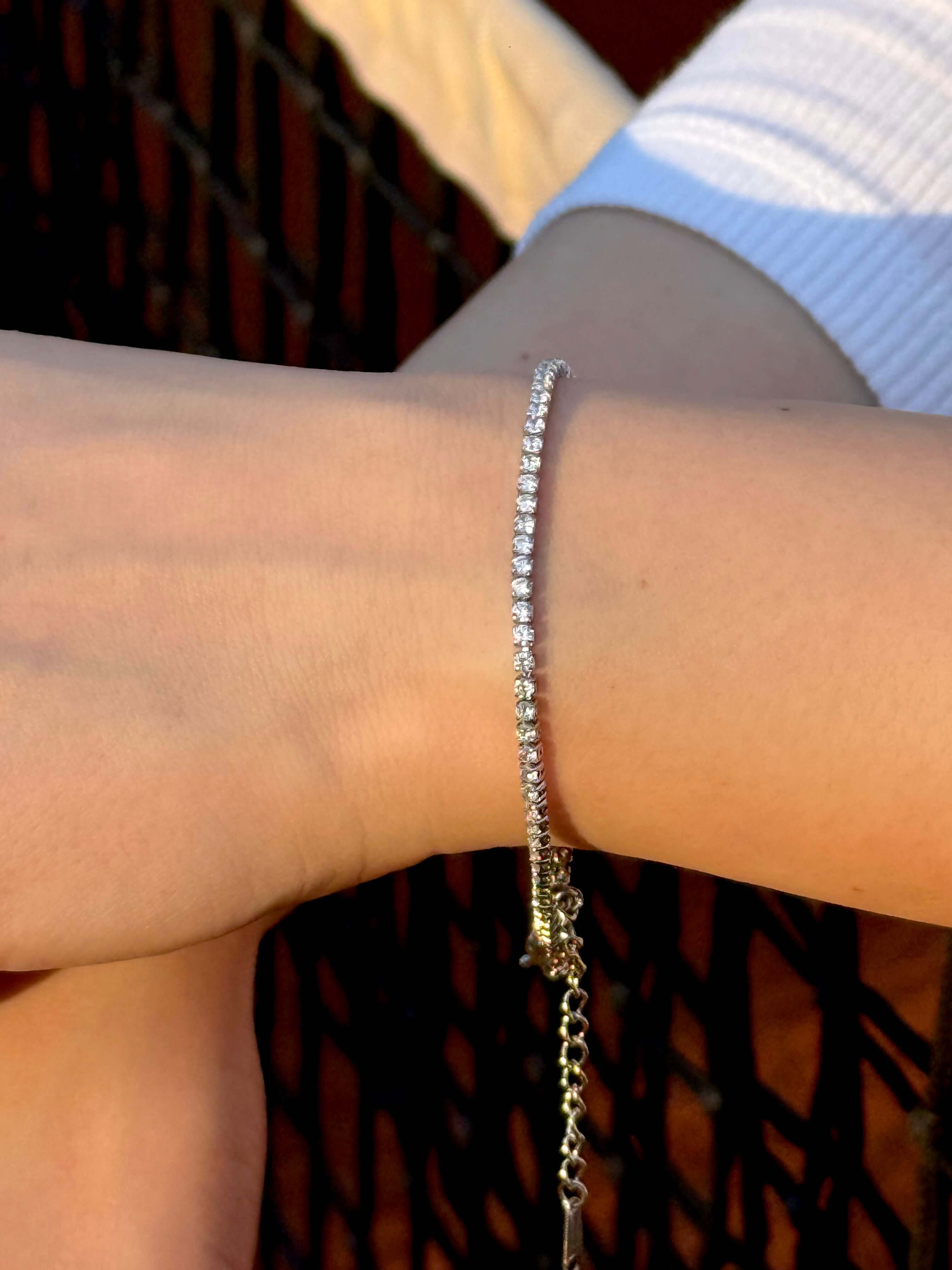 Гривна с инкрустирани камъни, носена на ръката, показваща елегантен дизайн и блясък.