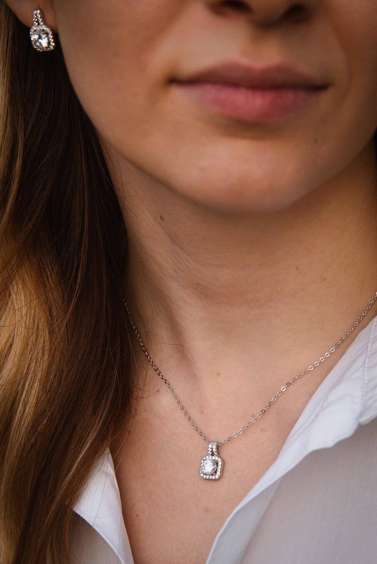 Елегантно сребърно колие с блестящ камък, носено от жена с минималистичен стил и облекло.