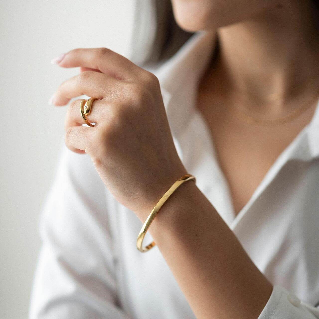 Woman wearing Ayra bracelet with 18K gold plating and stylish ring, showcasing elegant jewelry.