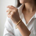 Woman wearing Ayra bracelet with 18K gold plating and stylish ring, showcasing elegant jewelry.