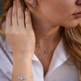 Млада жена носи сребърен комплект Хамса - обеци, гривна и колие, съчетаващи стил и защита.