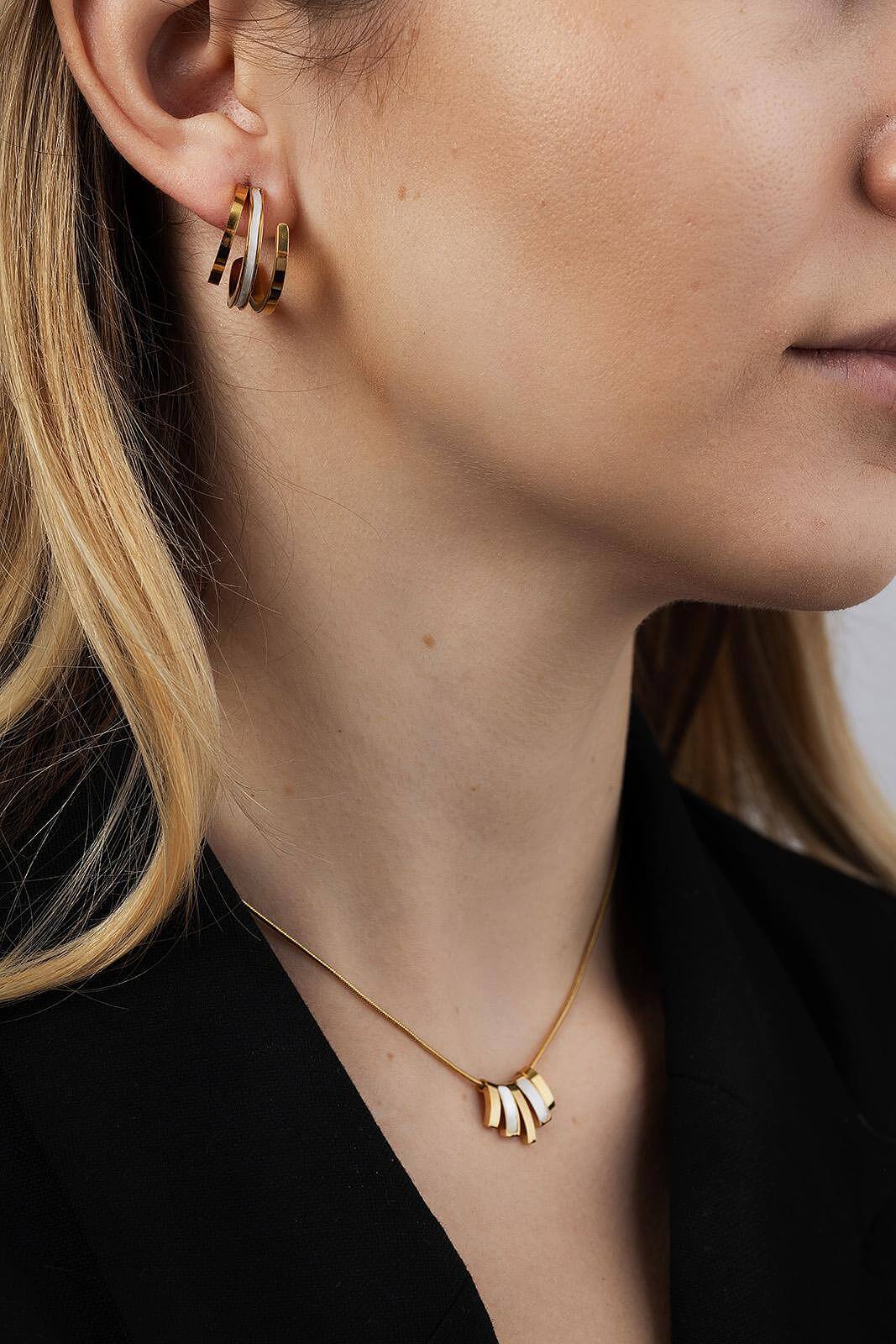 Златист комплект обеци и колие от медицинска стомана и седеф, носени от жена с дълга коса.