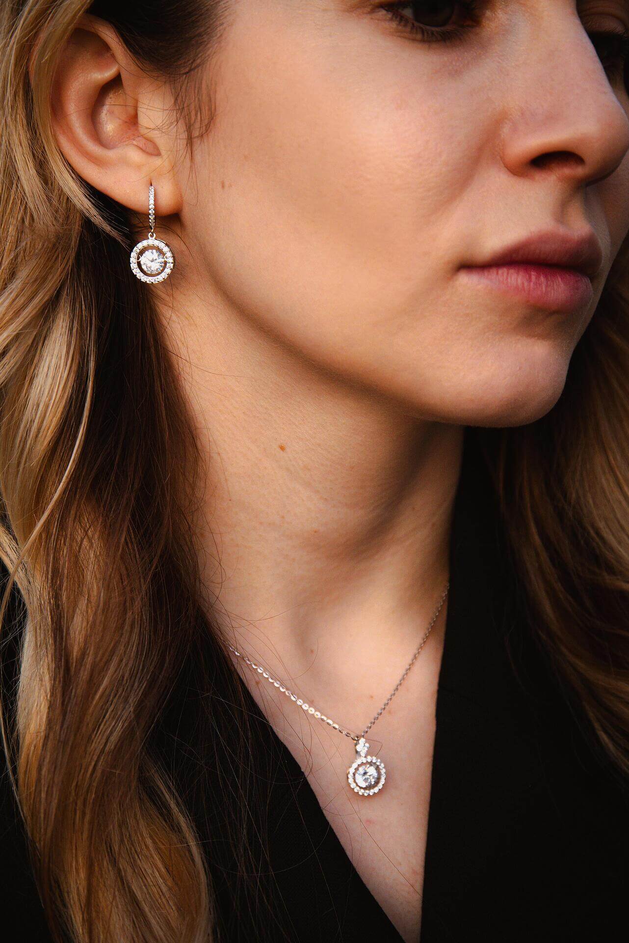 Жена с комплект обеци и колие от сребро S925 с блестящи камъни, излъчваща елегантност.