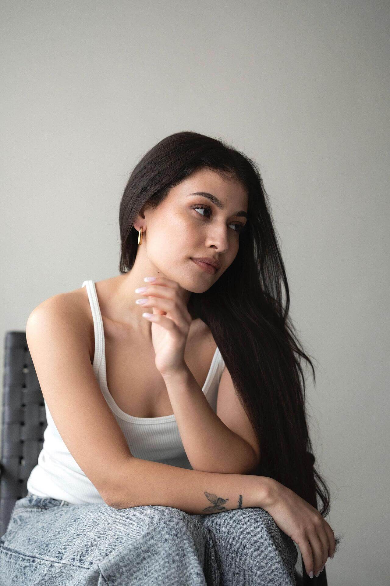 Woman wearing Liquid Drop earrings with 18K gold plating, posing thoughtfully in a stylish setting.