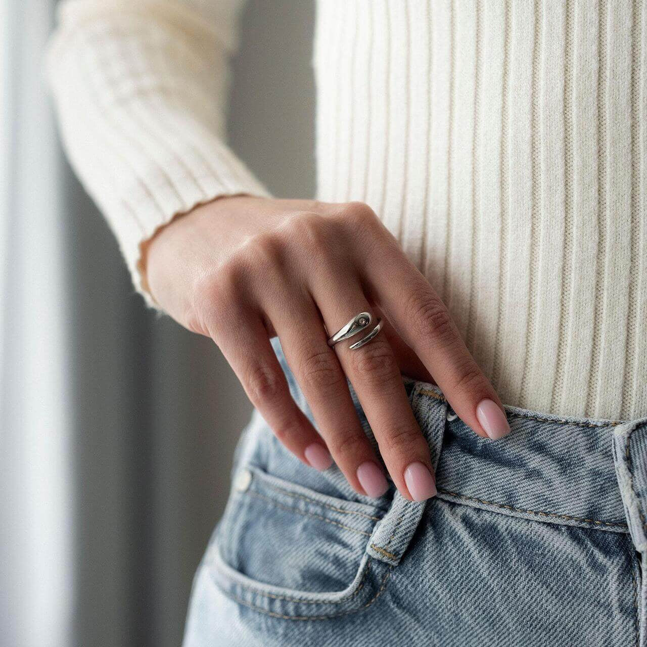 Жена носи ръчен пръстен Lyna с 18К златно покритие, съчетан с бели и сини дрехи.