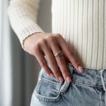 Жена носи ръчен пръстен Lyna с 18К златно покритие, съчетан с бели и сини дрехи.