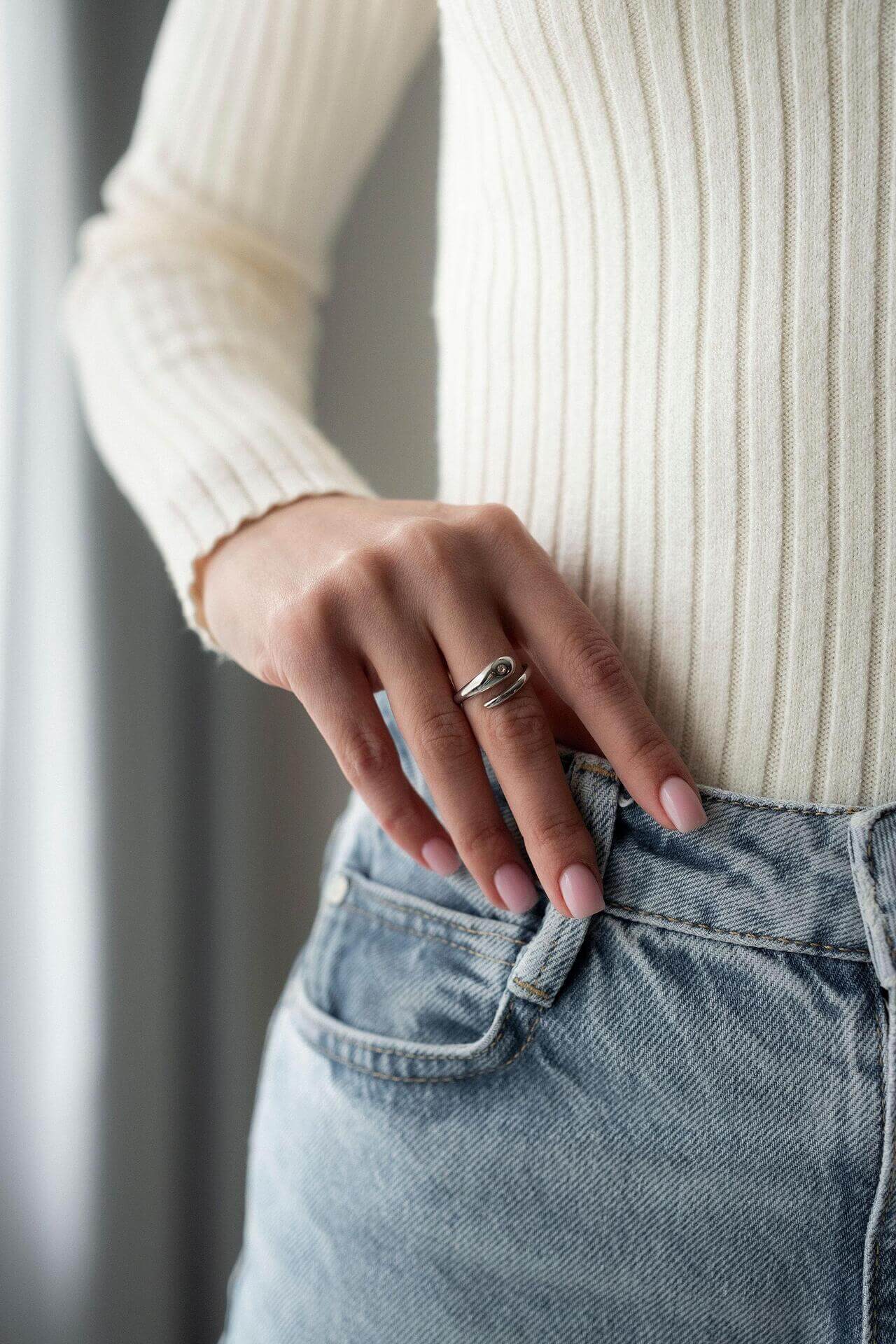 Жена носи ръчен пръстен Lyna с 18К златно покритие, съчетан с бели и сини дрехи.