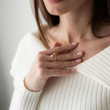 Elegant woman wearing a pearl ring with 18K gold plating, styled in a cozy white sweater.