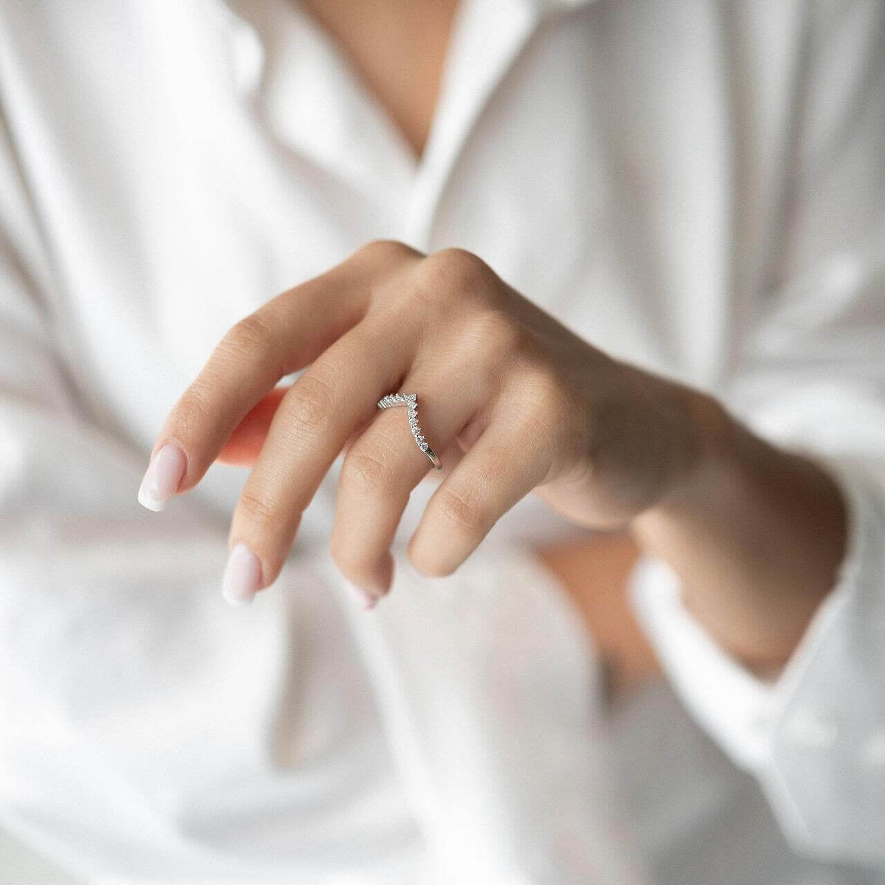 S925 silver ring with zirconia in V-shape worn on a woman's hand with a white shirt.
