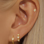 Сребърни обеци с 18K златно покритие и блестящи камъни, стилно представени на ухото.