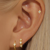 Сребърни обеци с 18K златно покритие и блестящи камъни, стилно представени на ухото.