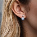 Сребърни обеци с окото на Хамса S925, носени от жена с дълга коса.