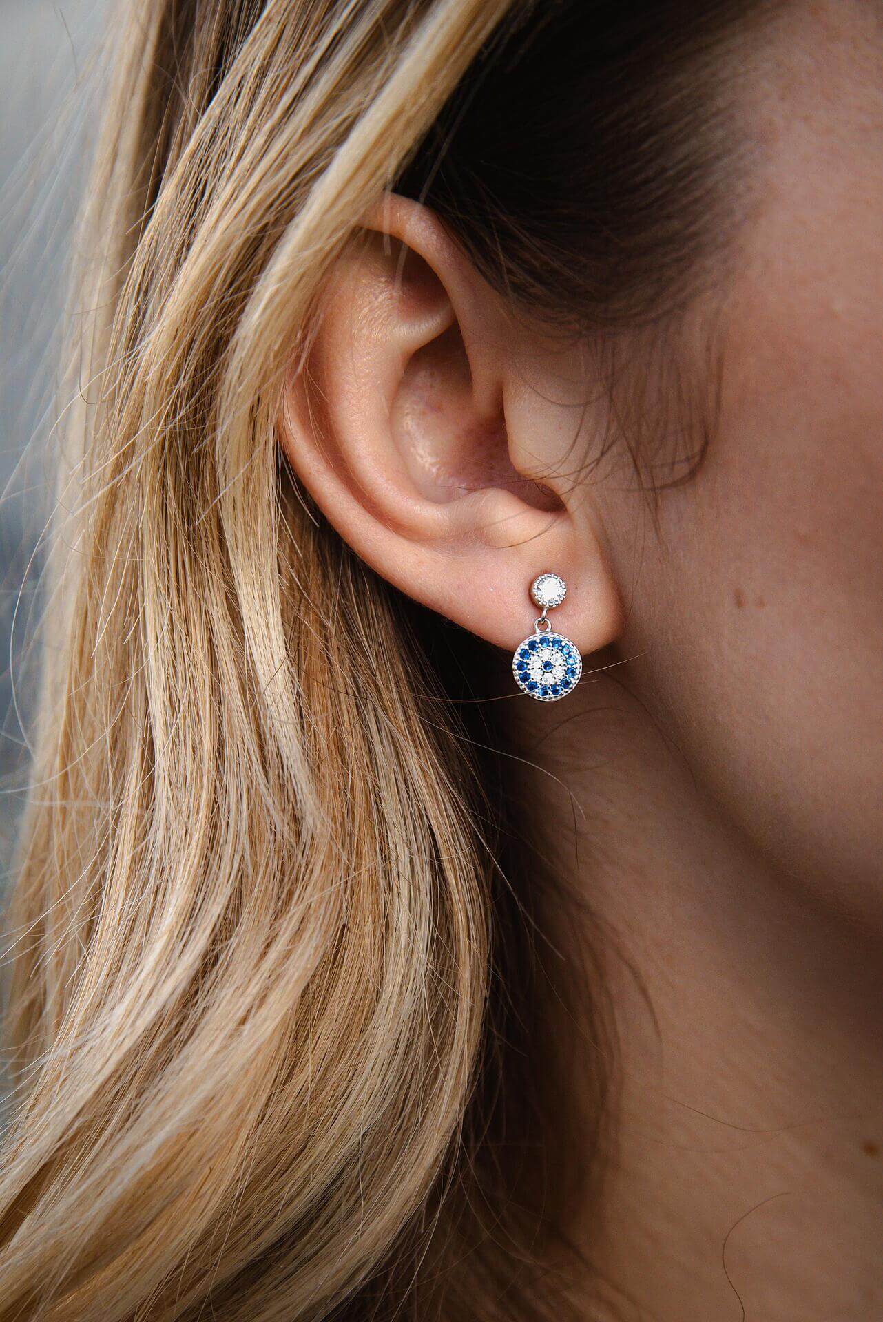 Сребърни обеци с окото на Хамса S925, носени от жена с дълга коса.