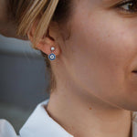 Сребърни обеци с окото на Хамса S925, носени от жена, излъчваща стил и символика.