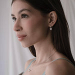 Дама с елегантни обеци във формата на сърце, с изразителен поглед и романтичен стил.