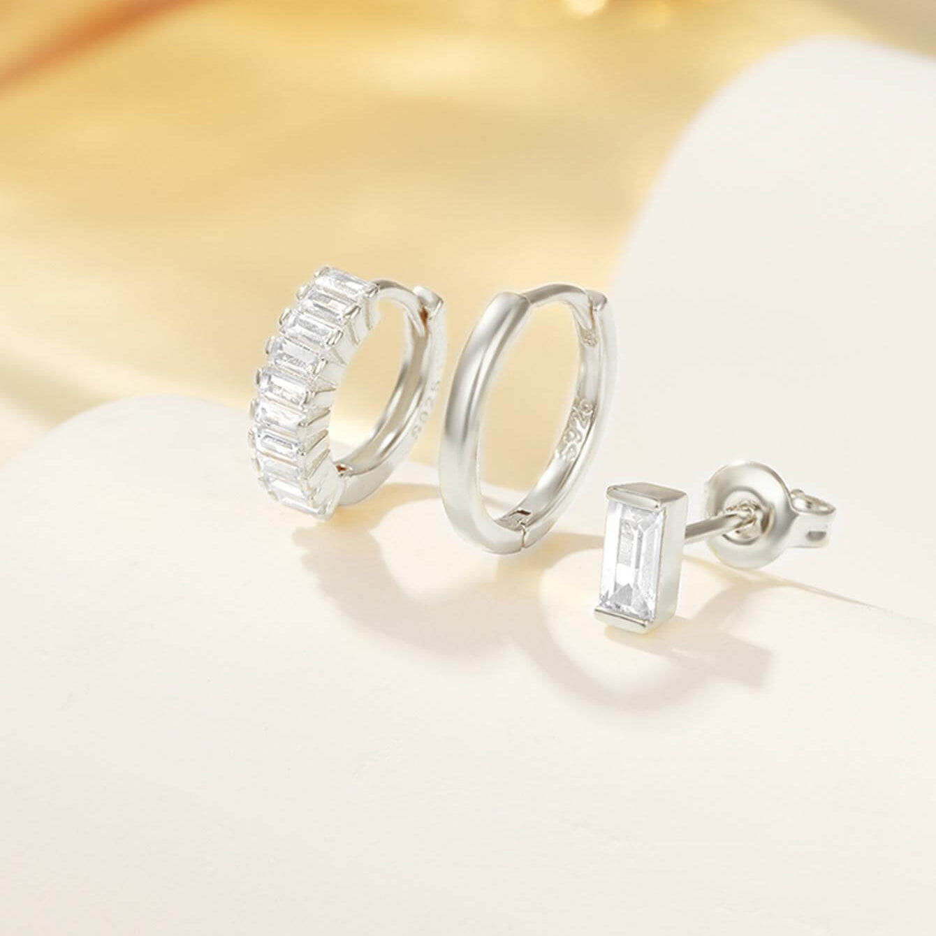 Сребърни обеци с кристали - комплект с две двойки, включващи класически и модерен стил, на светъл фон.