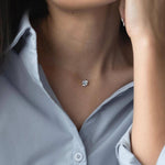 Сребърно колие с циркон на фона на жена в светло синя риза, акцентиращо на елегантност и стил.