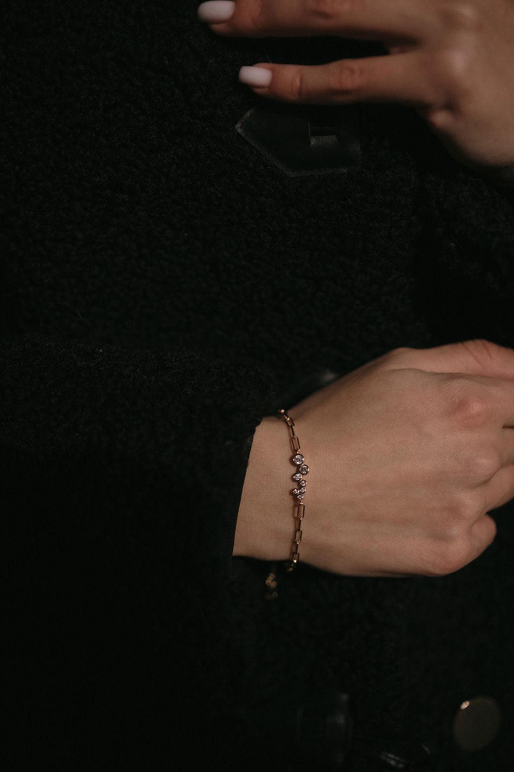 Елегантна сребърна гривна с 18К златно покритие и камъни циркон, носена на ръка.