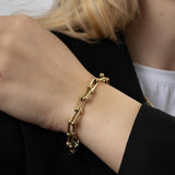 Твърда златиста гривна Signature върху ръка, изработена от медицинска стомана, елегантен и минималистичен дизайн.