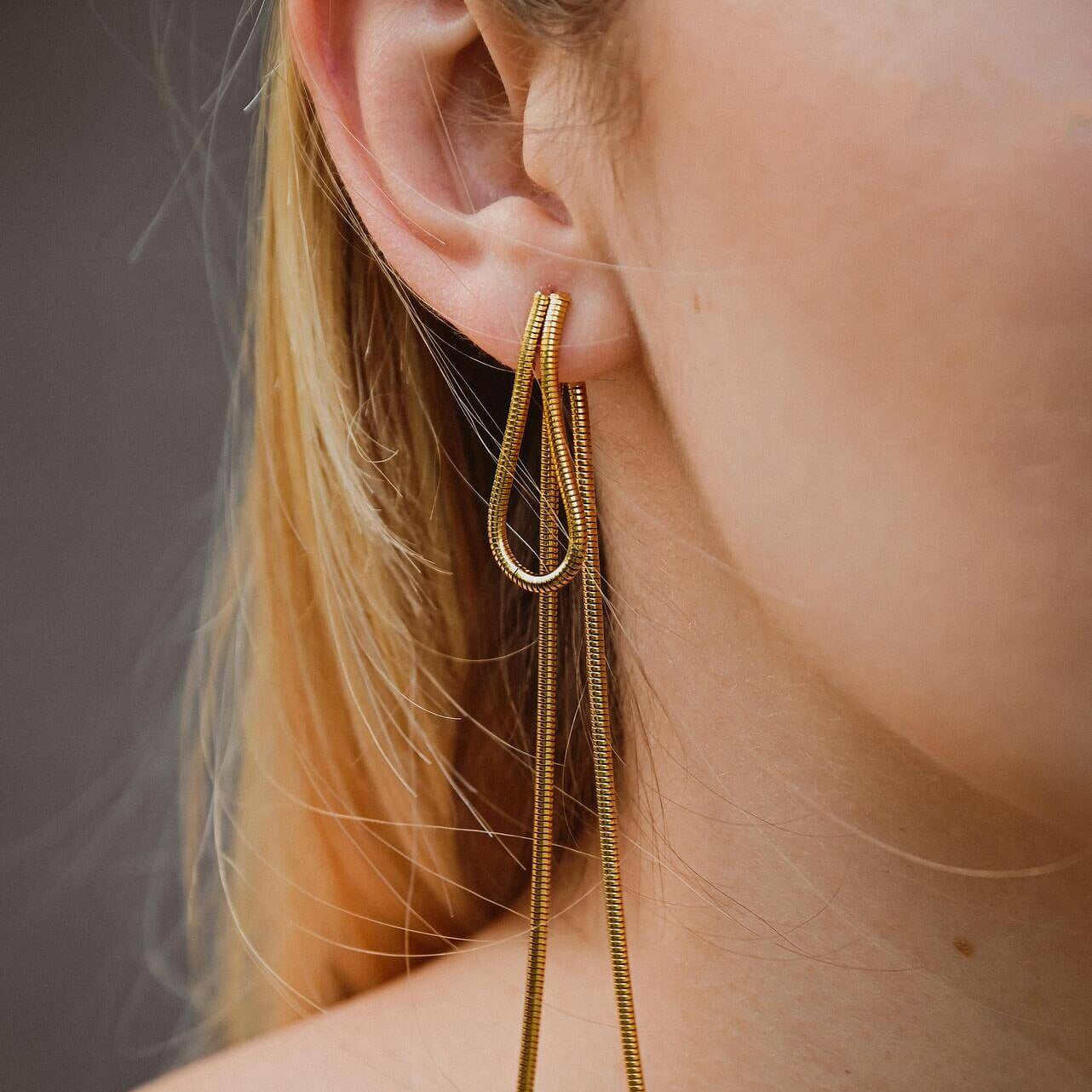 Модерни висящи обеци в златист цвят, съчетаващи елегантност и стил.