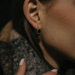 Златисти обеци с кристали, носени от жена с елегантен шал, подчертаващи модния стил.