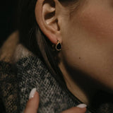 Златисти обеци с кристали, носени от жена с елегантен шал, подчертаващи модния стил.